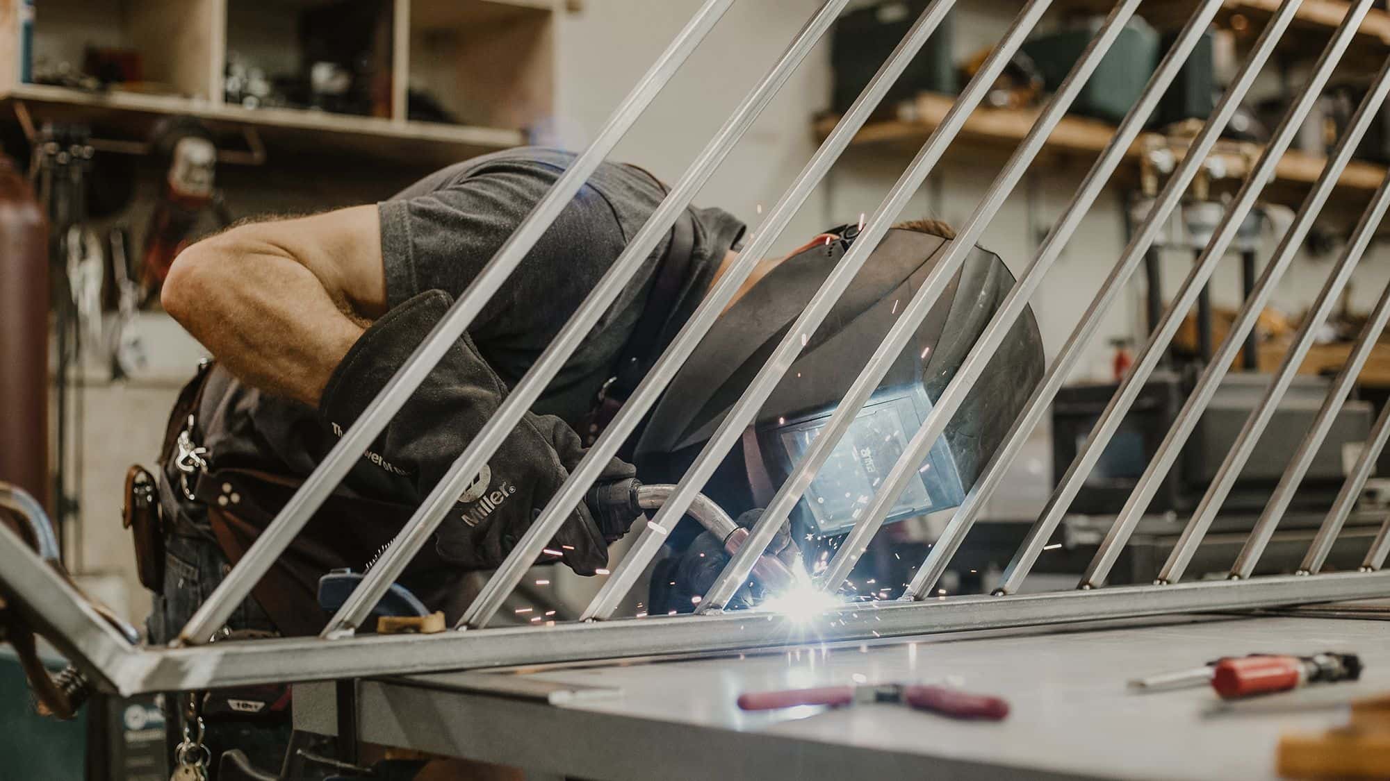 Man in a welding helmet and gloves welding at a clean workstation