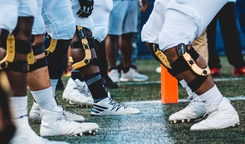 football players on field wearing leg braces