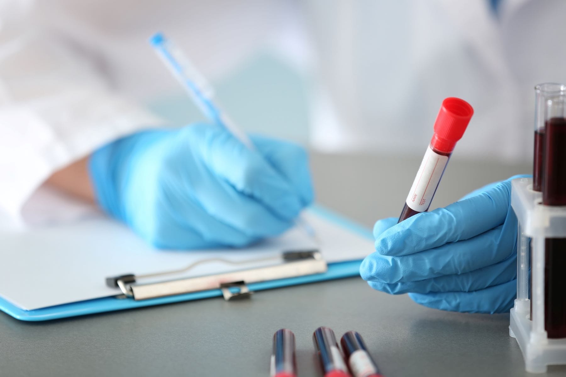 Woman working with blood sample in test tube at table