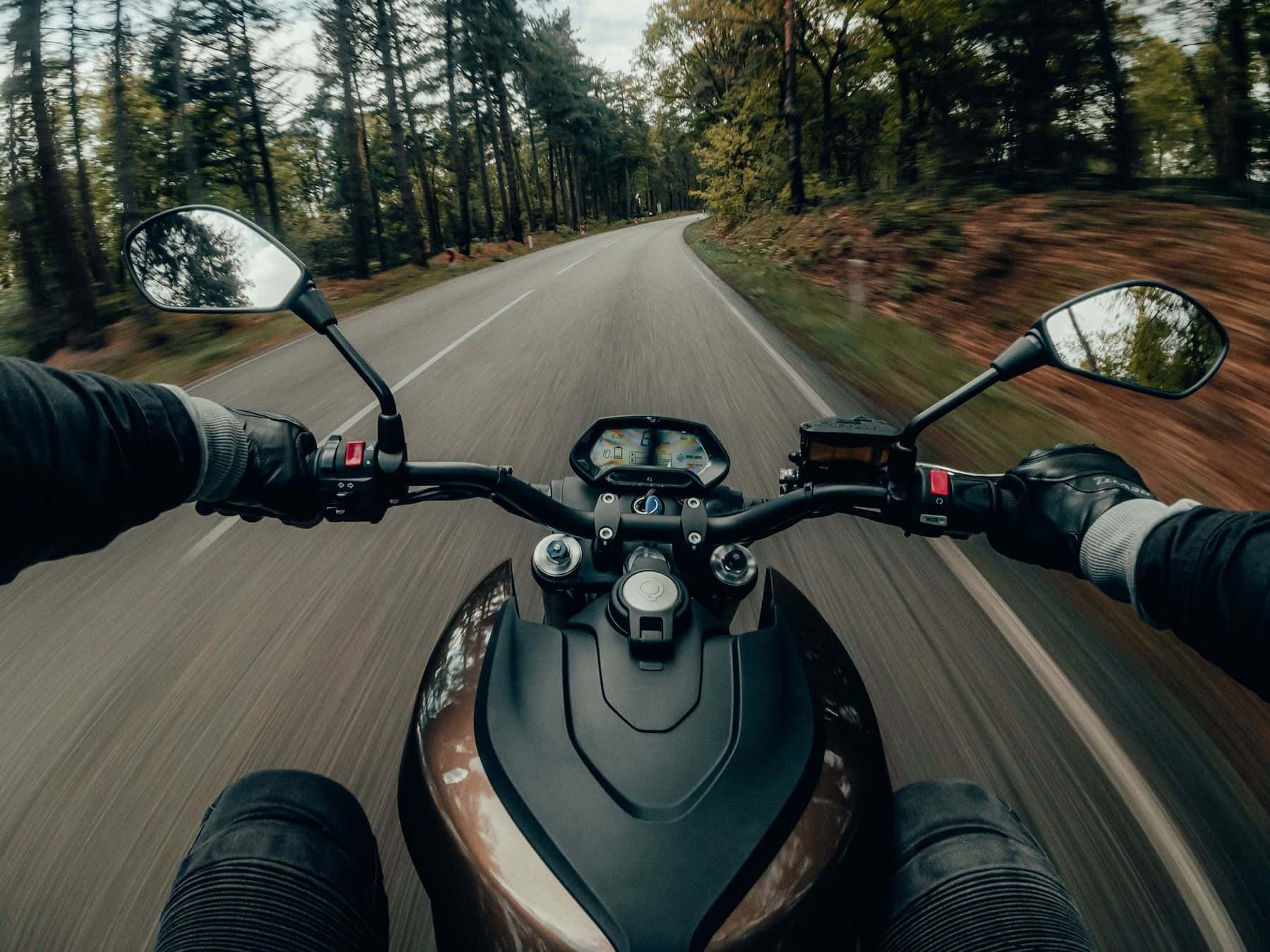 Motorcyclist riding down tree lined backroads