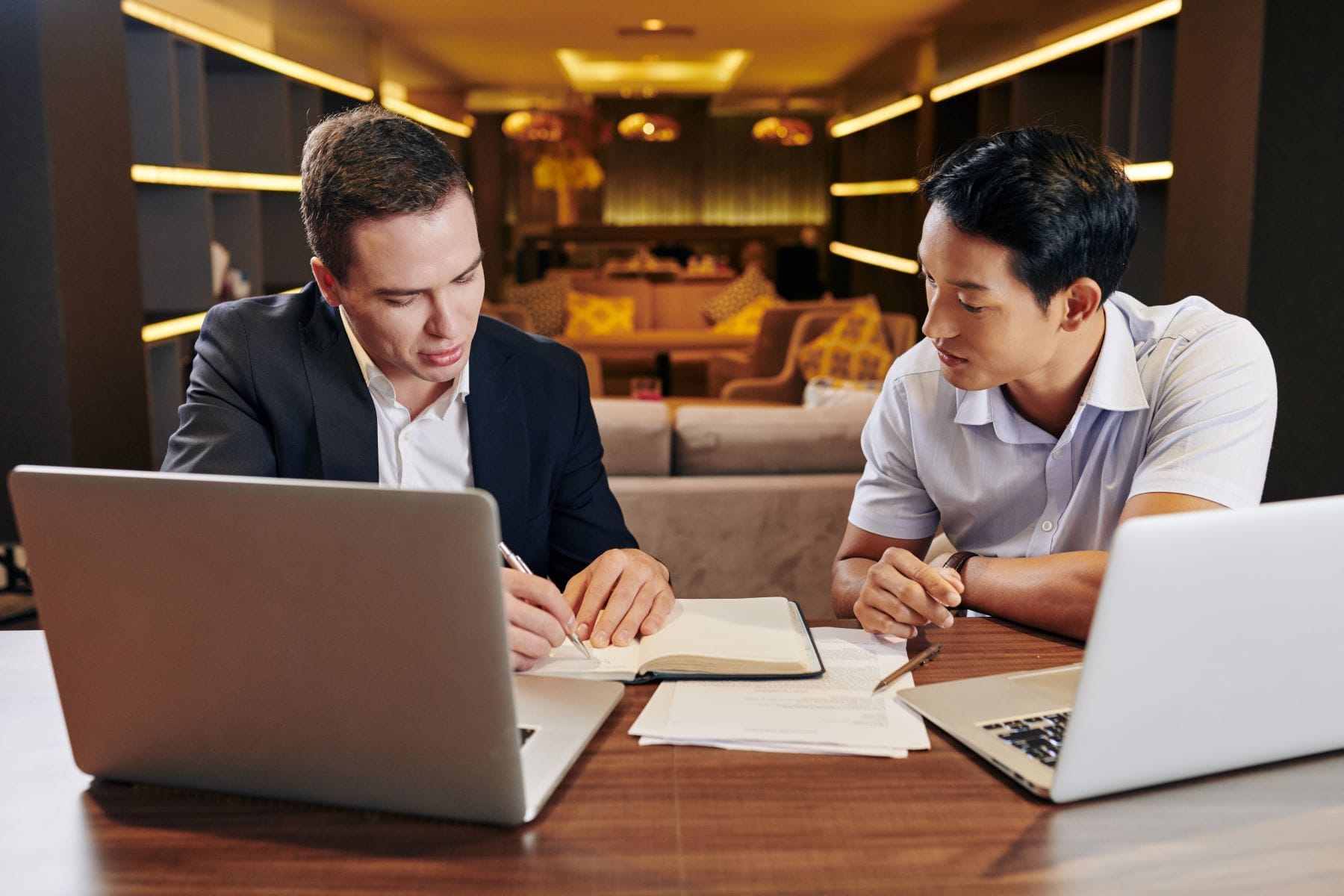 Two professionals working on laptops